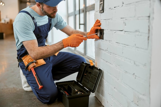 Photo Électricien mâle fixant la prise murale électrique avec un tournevis