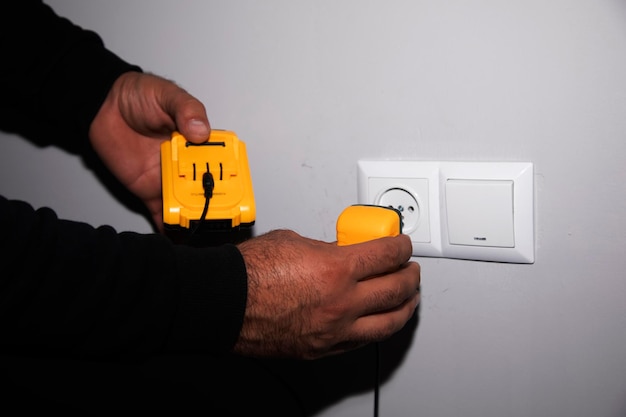 électricien masculin avec prise d'alimentation jaune à la main