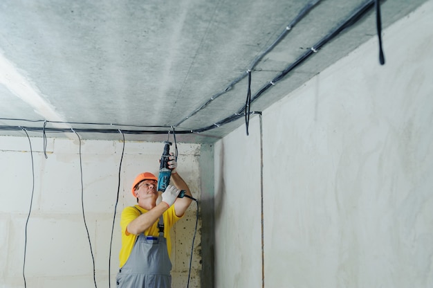 Photo un électricien perce un plafond avec un perforateur.