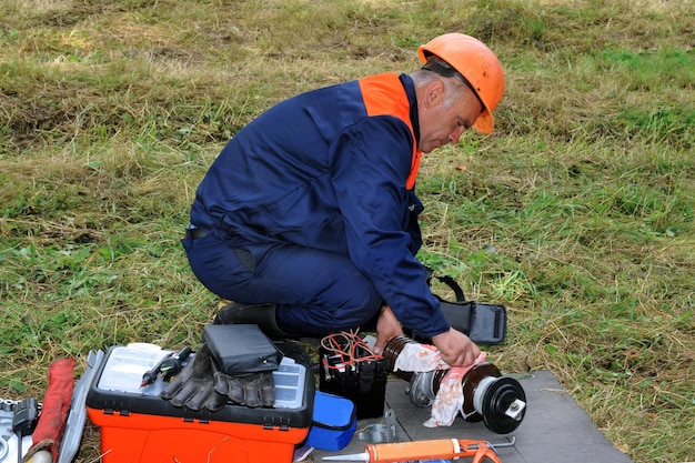 Un électricien vérifie et prépare un isolateur en céramique haute tension pour le remplacement