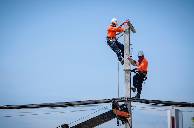 Des électriciens grimpent sur des poteaux électriques pour installer et réparer des lignes électriques.