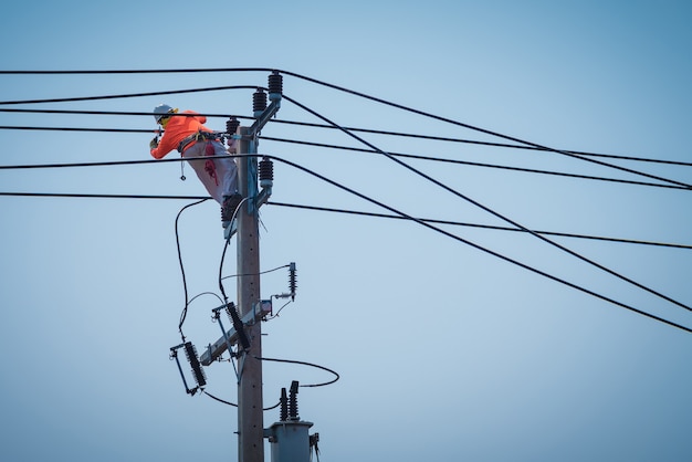 Des électriciens grimpent sur des poteaux électriques pour installer et réparer des lignes électriques.