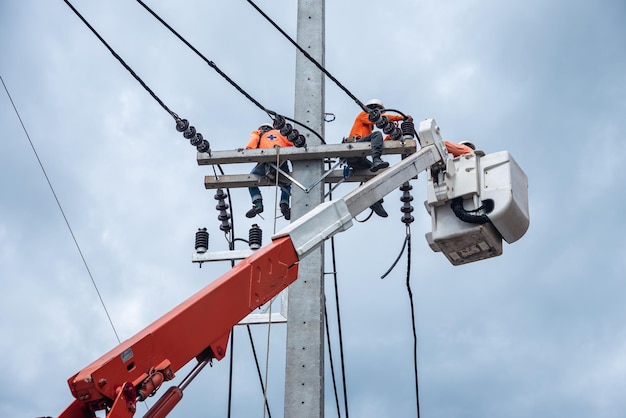 Des électriciens grimpent sur des poteaux électriques pour installer et réparer des lignes électriques.