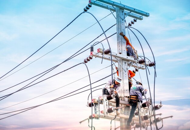 Photo les électriciens montent sur des poteaux électriques pour installer et réparer des lignes électriques certains techniciens ne portent pas de casque peuvent être dangereux