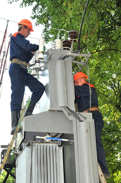 Les électriciens remplacent un isolateur défectueux dans une sous-station électrique