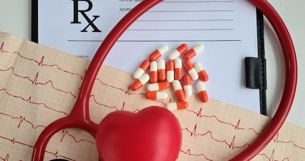 Électrocardiogramme cardiaque avec stéthoscope et ordonnance avec des pilules en clinique