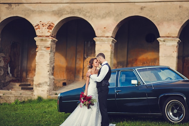 élégant couple marié et mariée près de voiture classique