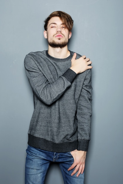 Élégant jeune bel homme. Portrait de mode studio sur espace gris