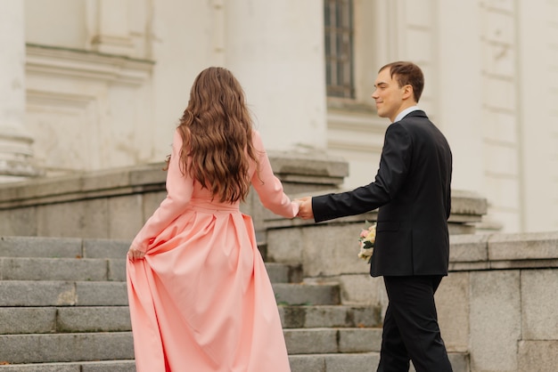 Photo Élégant juste joyeux. couple de mariage. heureuse mariée et le marié marchant près du vieux château. bouquet de mariée mariage de fleur