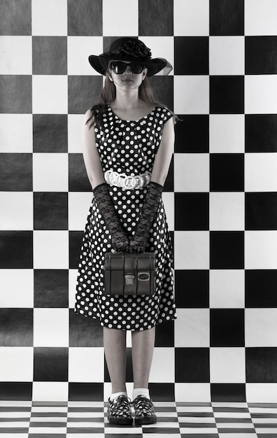 élégante adolescente en robe à pois sur un fond d'échecs