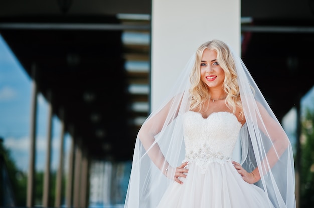 Elégante blonde aux yeux bleus fashion mariée au grand hall de mariage sur le tapis rouge