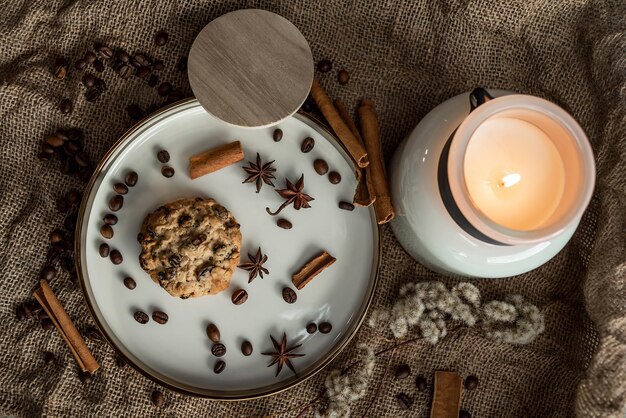 Une élégante composition de bougies, assiettes à bordure dorée, biscuits et épices - anis, cannelle