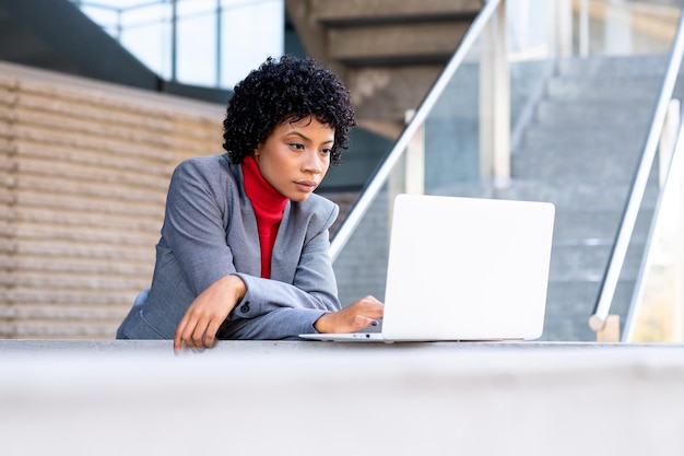 Une élégante femme afro-américaine travaillant sur son ordinateur portable dans un immeuble de bureaux