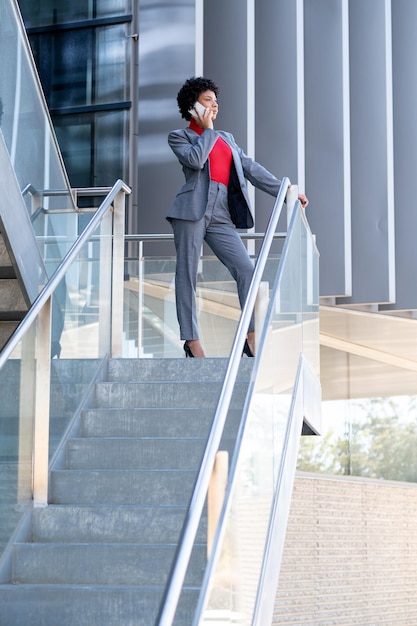 Une élégante femme afro-américaine utilisant le téléphone dans un immeuble de bureaux au travail