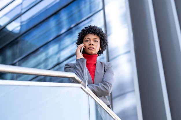 Une élégante femme afro-américaine utilisant le téléphone dans un immeuble de bureaux au travail