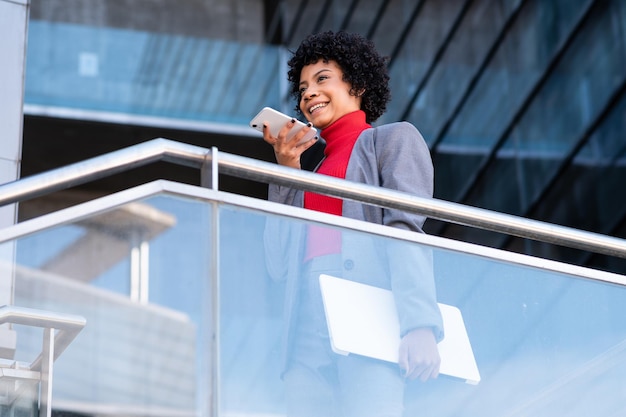 Une élégante femme afro-américaine utilisant le téléphone dans un immeuble de bureaux au travail