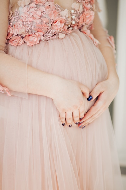 Élégante future mère posant dans une robe longue tenant son ventre