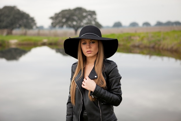 Élégante jeune femme avec un beau chapeau sur le terrain