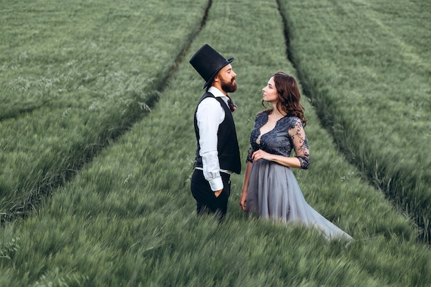 Élégante mariée et le marié marchant et posant sur champ vert