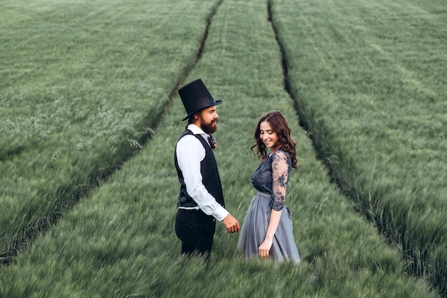 Photo Élégante mariée et le marié marchant et posant sur champ vert