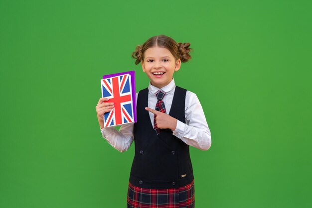 L'élève aime beaucoup la matière scolaire qu'est l'anglais. l'élève pointe du doigt le manuel d'anglais. connaissances et éducation. étudier à l'école. fond vert isolé.