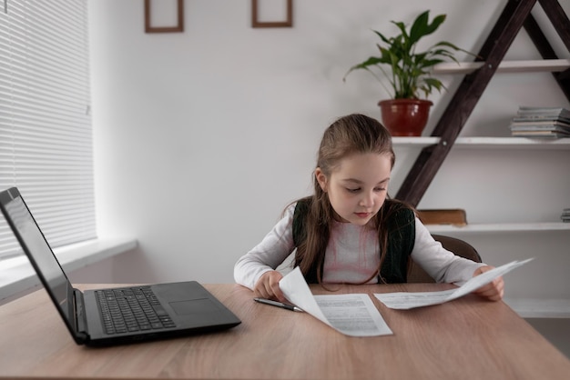 Un élève caucasien s'est concentré sur les devoirs et les tests de mathématiques tout en étudiant à distance à la maison avec un ordinateur portable dans la chambre Concept d'éducation à l'école primaire Enfant de 89 ans