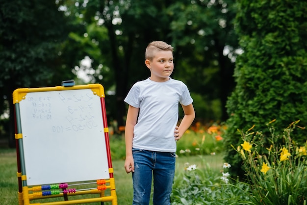 L'élève écrit Des Leçons Au Tableau Et S'entraîne En Plein Air. Retour à L'école, Apprendre Pendant La Pandémie.