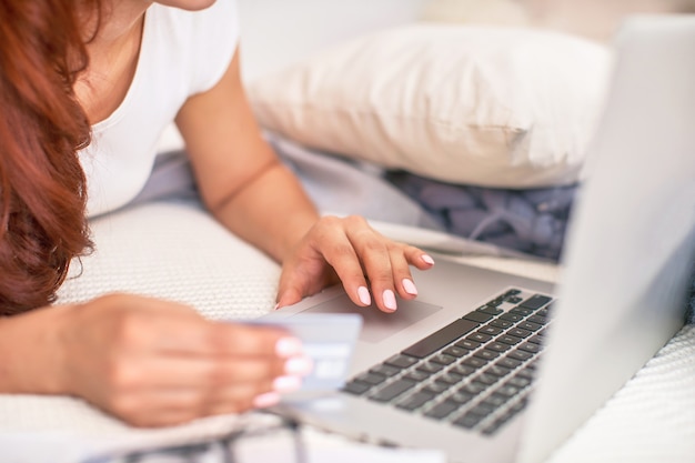 L'élève est heureux de communiquer avec ses amis via Internet. enseignement à domicile, travail et études, nouvelles connaissances. adolescent heureux sur le lit avec ordinateur. étudiante allongée sur le lit en souriant.