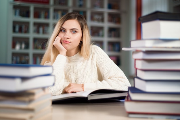 Un élève fatigué étudie dans la bibliothèque de l'école.