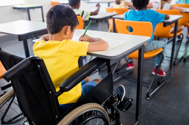 Un élève en fauteuil roulant travaillant à son bureau