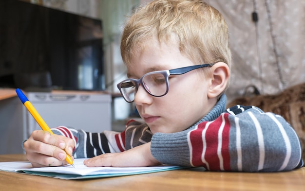 Un élève de première année concentré apprenant à écrire et à faire ses devoirs.