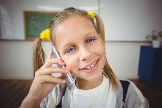 Élève souriant téléphonant avec smartphone dans une salle de classe