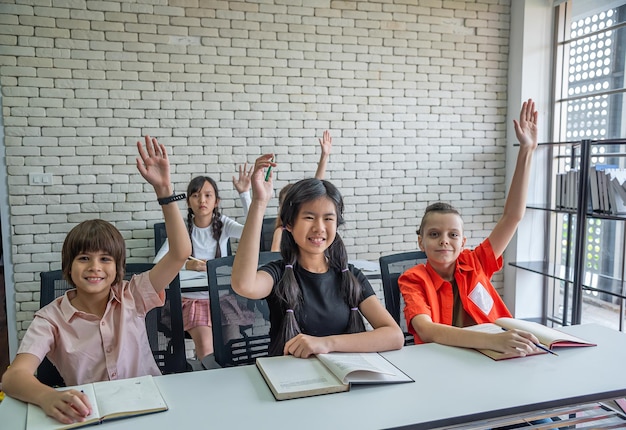 Les élèves du primaire lèvent la main pour demander au professeur de classe