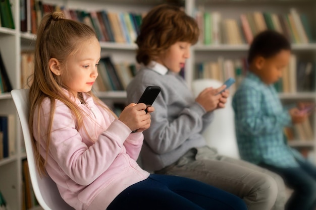 Les élèves jouent à des jeux sur leurs smartphones en pause assis sur des chaises en classe sélective