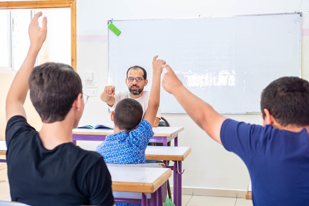 Les élèves lèvent la main pour assister et répondre à la question de l'enseignant