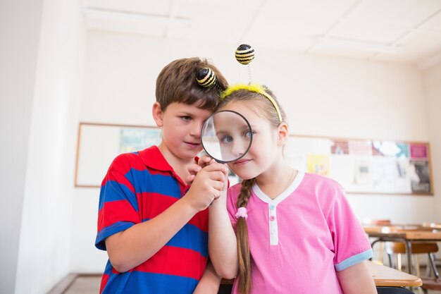 Photo Élèves mignons regardant à travers la loupe