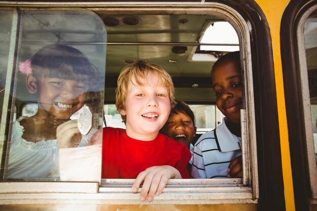 Photo Élèves mignons, souriant à la caméra dans le bus scolaire