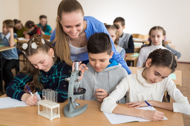 Les élèves utilisant des béchers scientifiques et un microscope à l'école primaire