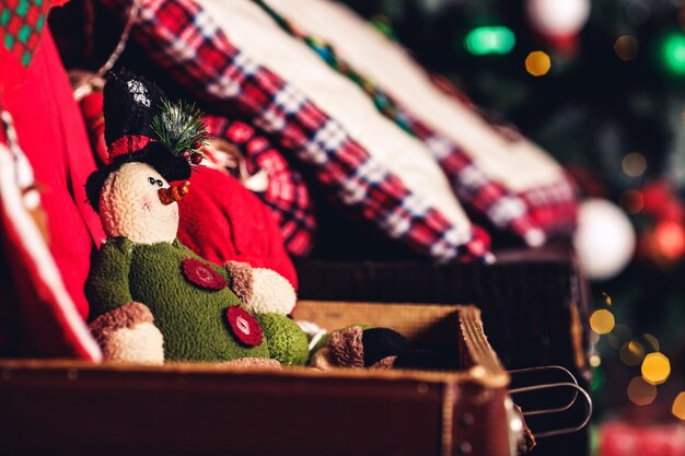 Elfe jouet de Noël assis sur une valise sur la surface de l'arbre de Noël.