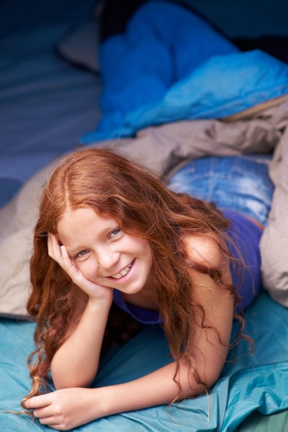 Elle aime le camping Portrait d'une jeune fille heureuse allongée dans sa tente en camping