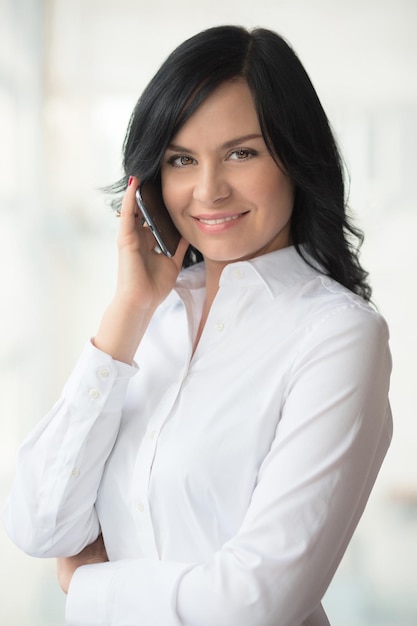 Elle aime passer du temps, parler au téléphone. Portrait de col blanc au bureau