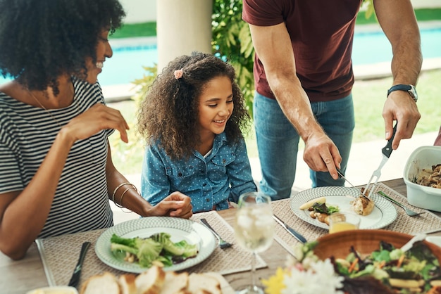 Elle a l'appétit de son papa Photo d'une adorable petite fille qui savoure un repas avec ses parents à l'extérieur