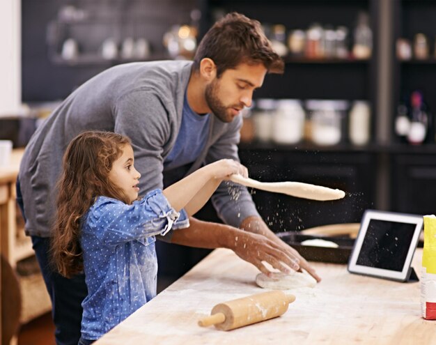 Elle a du talent Photo d'un père et de sa fille travaillant avec de la pâte à pizza dans la cuisine