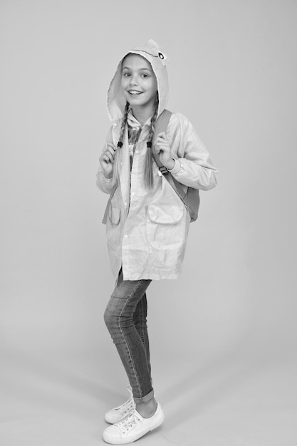 Elle est cool Heureux petit enfant portant une veste de pluie mode sur fond jaune Petit enfant souriant avec un look d'automne Petite fille prête pour un voyage pluvieux Adorable petit sourire d'enfant en tenue de pluie verte