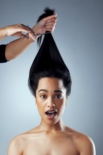 Elle est sur le point de changer sa vie Prise de vue en studio d'une jeune femme se faisant couper les cheveux sur un fond gris