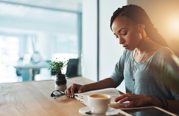 Elle fait des recherches Photo recadrée d'une jeune femme lisant un livre tout en travaillant tard dans son bureau