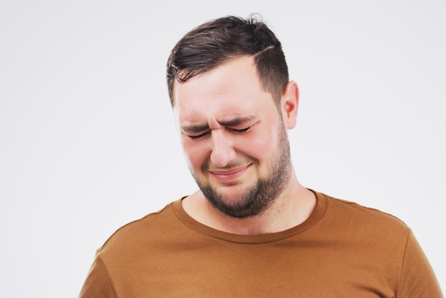 Elle m'a brisé le coeur Prise de vue en studio d'un jeune homme pleurant en se tenant debout sur un fond gris