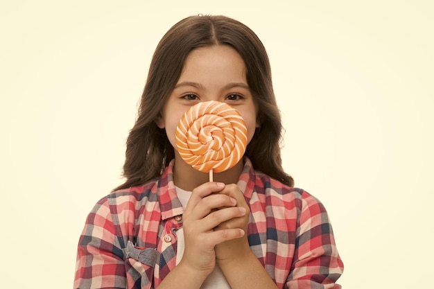 Elle ne peut pas vivre sans bonbons Fille mignon visage souriant tient douce sucette devant le visage de près Bonbons dans les portions appropriées ok Fille aime bonbons sucette isolé fond blanc