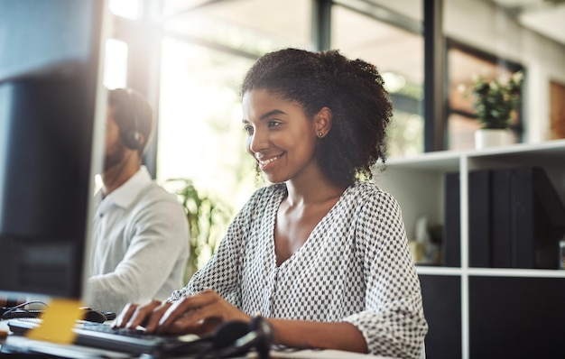 Elle a personnellement investi dans l'entreprise Photo d'une jeune femme d'affaires travaillant sur son ordinateur avec son collègue en arrière-plan