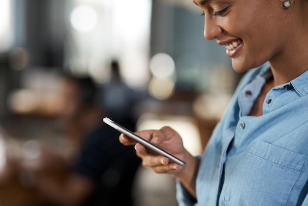 Elle a planifié sa journée de travail sur son téléphone Photo d'une jolie jeune femme d'affaires utilisant un téléphone portable dans un bureau